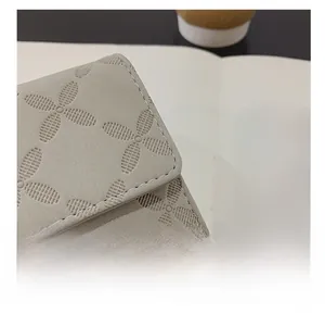 Détail du portefeuille en cuir gris avec gaufrage floral et couture blanche de qualité