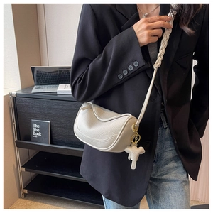 Detail of off-white dumpling bag with braided strap and cute elephant charm accessory