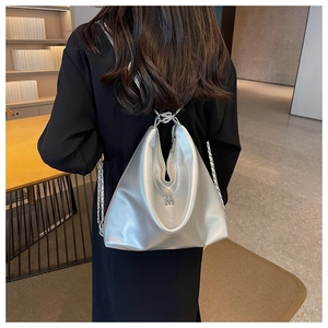 Rear view of a model wearing a large metallic silver hobo bag with an M metal logo
