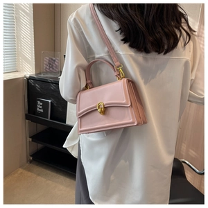Detail of light pink leather crossbody bag with golden twist lock on white shirt