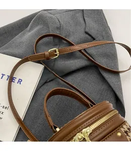 Close-up of brown leather cylinder bag with metal zipper and adjustable strap