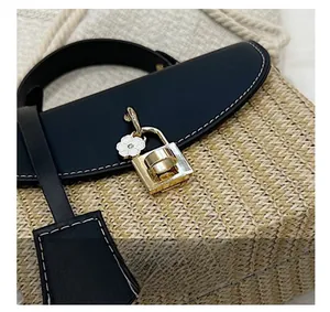 Détail du sac en paille tissée avec garniture en cuir noir et boucle en métal doré