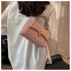 Detailed view of pink leather crossbody bag with elegant gold knot clasp on model