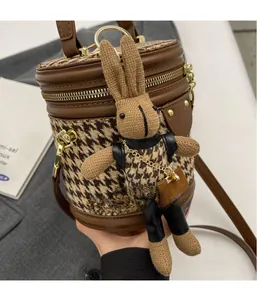 Detail view of houndstooth bucket bag with brown leather trim and a cute rabbit charm