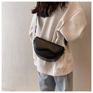 Detail of a matte black saddle crossbody bag with Fashion & Classic embossed lettering