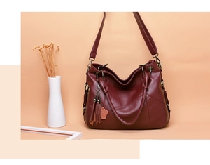 Détail d'un grand sac fourre-tout bordeaux avec coutures et pendentif à franges chic