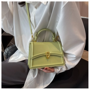 Detail of mint green crossbody bag with golden ring lock worn on a white shirt