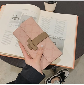Détail d'un portefeuille long rose avec texture grainée et fermoir en T marron élégant