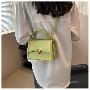 Crossbody wear of light green leather handbag featuring elegant gold metal twist lock buckle