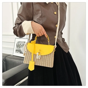 Détail du sac à main en paille avec rabat en cuir jaune et fermoir rotatif en métal
