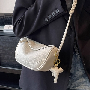 White lychee leather saddle crossbody bag with woven strap and elephant charm accent