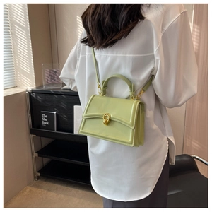 Detail of pistachio green leather crossbody bag with gold buckle on a white shirt
