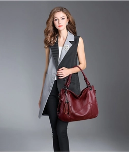 Détail d'un grand sac cabas bordeaux avec texture en cuir souple et pendentif à pompon