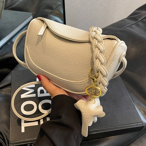 Chic beige lychee leather dumpling bag with woven handle and cute elephant charm