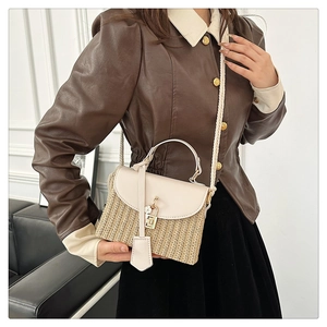 Détail d'un sac bandoulière en paille avec rabat en cuir blanc et fermoir fleuri porté