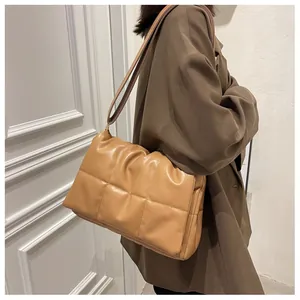 Détail du sac bandoulière kaki matelassé avec motif à losanges porté par le mannequin