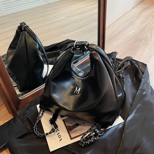 Minimalist black soft leather hobo bag with metallic M logo and chain strap detail