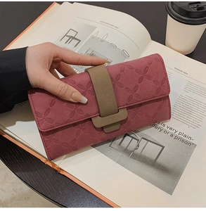 Détail du portefeuille rose avec gaufrage floral et sangle à boucle en cuir véritable