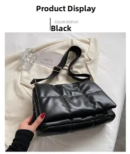 Détail d'un sac bandoulière matelassé noir avec boucles dorées posé sur un blazer blanc
