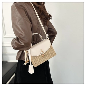 Sac à main en paille avec rabat en cuir blanc et fermoir doré porté par un mannequin