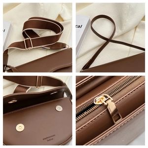 Detail view of coffee brown crossbody bag with dual straps and golden hardware zipper