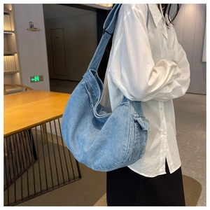 Detail of light blue denim messenger bag with adjustable strap and side utility pocket