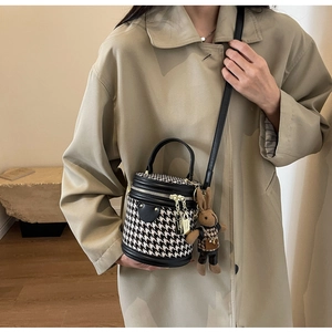 Detail of houndstooth bucket bag with leather trim and cute rabbit plush charm
