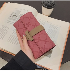 Détail d'un long portefeuille en cuir rose avec motifs trèfle et fermeture à boucle