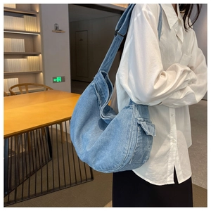 Detail of light blue denim hobo messenger bag with side cargo pocket on model