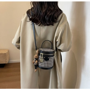Detail of vintage houndstooth bucket bag with black leather trim and rabbit charm