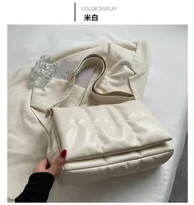 Détail d'un sac bandoulière matelassé blanc crème avec motif brodé et large sangle