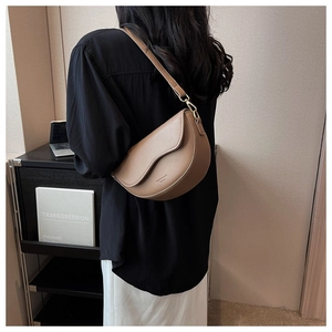 Detail of a brown matte saddle bag with wavy edge design and gold metal buckle hardware