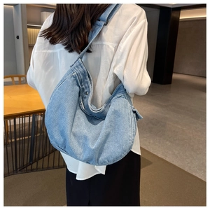 Detail of light blue washed denim hobo bag showing texture and wide strap on model