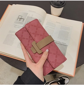 Détail d'un long portefeuille rose foncé avec gaufrage floral et boucle décorative marron