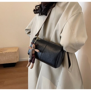 Détail d'un sac Boston en cuir noir texturé avec une large bandoulière jacquard rétro