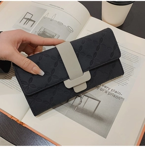 Gros plan d'un portefeuille noir avec gaufrage trèfle et boucle grise élégante pour femme