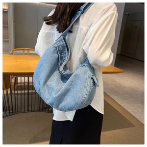Detail shot of light blue washed denim messenger bag with utility side pocket design