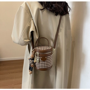 Woman wearing a vintage houndstooth bucket bag with leather trim and bear pendant charm