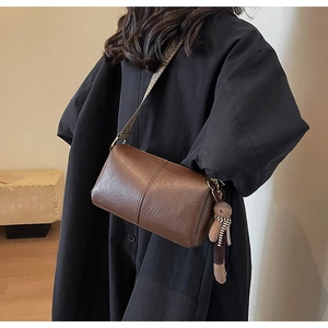 Détail du sac polochon en cuir marron avec bandoulière jacquard et charm ours