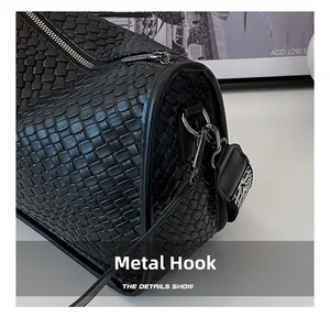 Close-up of black woven texture shoulder bag with silver metal hooks and woven strap