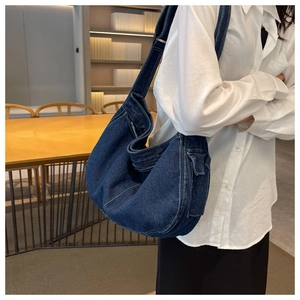 Close-up of a large navy denim hobo bag featuring contrast stitching and side pockets