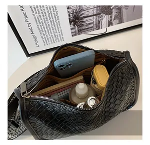 Detailed interior view of black woven crossbody bag showing spacious capacity and daily items