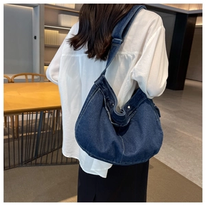 Detail of blue denim hobo messenger bag with contrast stitching and wide shoulder strap