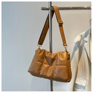 Détail d'un sac bandoulière matelassé marron caramel avec une texture douce et puffy