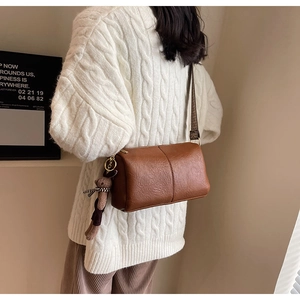 Sac cylindrique marron avec pendentif ours porté sur un pull en maille confortable