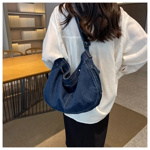 Close-up of a deep blue denim hobo bag with contrast stitching and adjustable wide strap