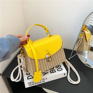 Sac à main en cuir jaune et paille avec serrure fleurie dorée sur un livre design