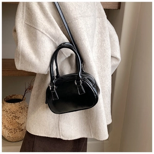 Detail of minimalist black patent leather mini Boston bag with silver metal hardware