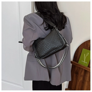 Close-up of black woven shoulder bag with a stylish striped decorative strap on a model