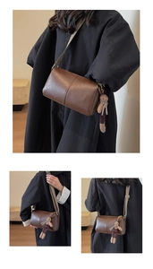 Detail of dark brown cylinder bag with lychee texture and woven ethnic strap